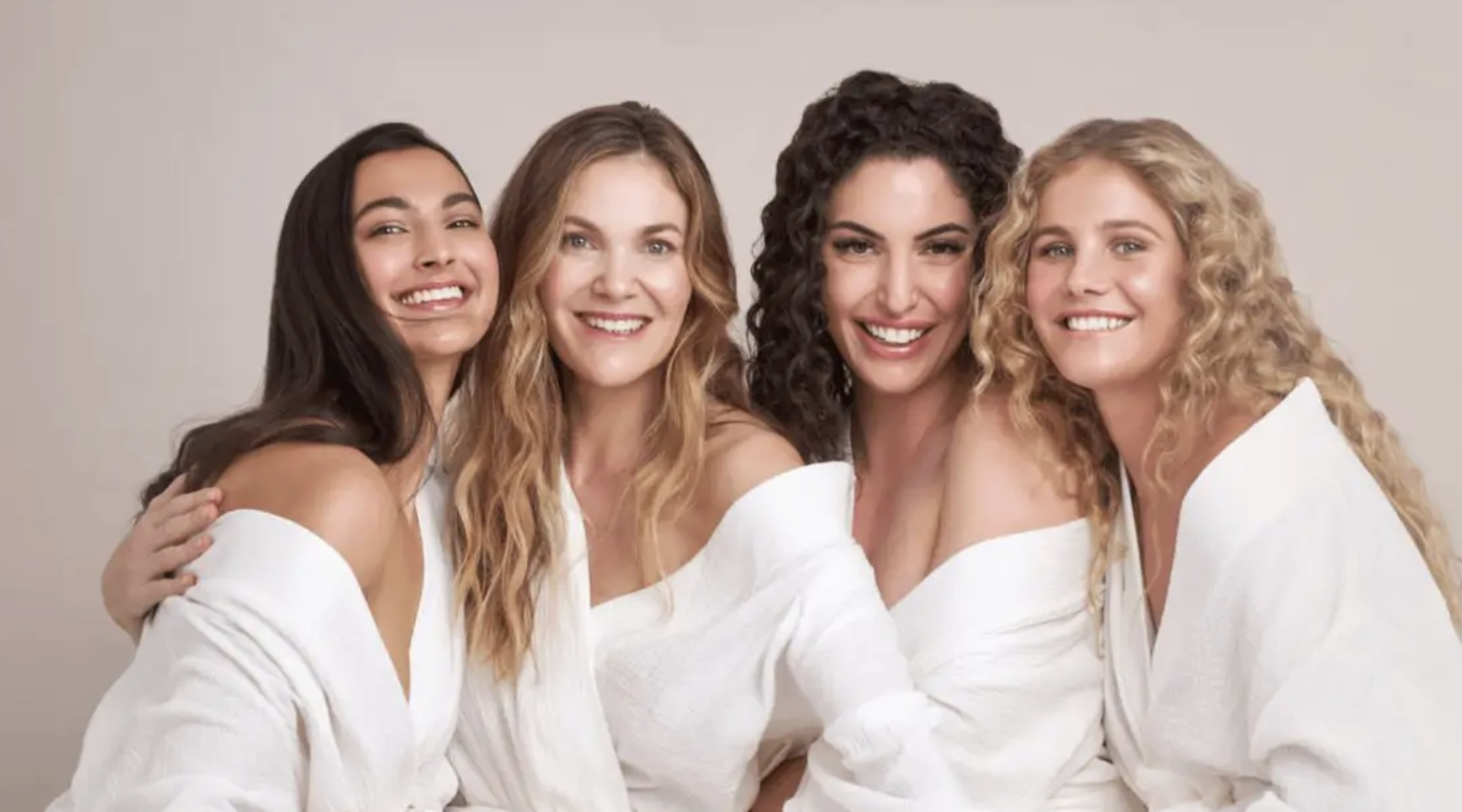 Four Juvly clients in white robes, smiling together