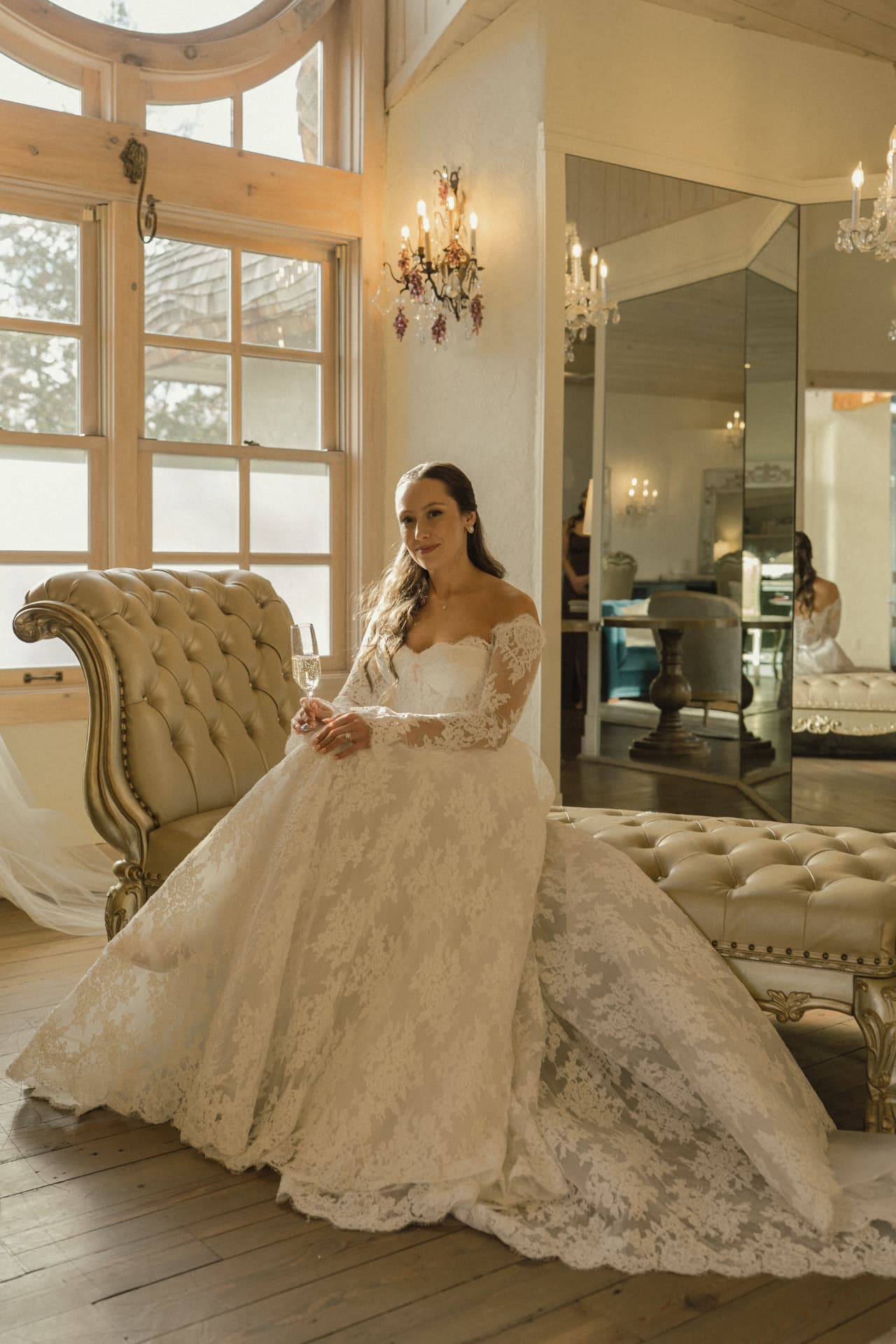 Bride in a lace ballgown with champagne in the bridal suite