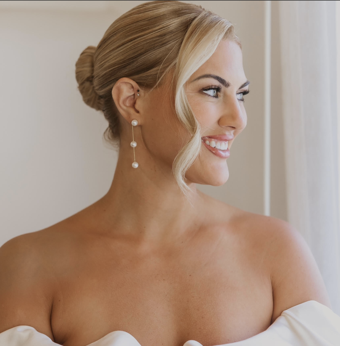 Bride with a soft chignon and pearl earrings on her wedding morning